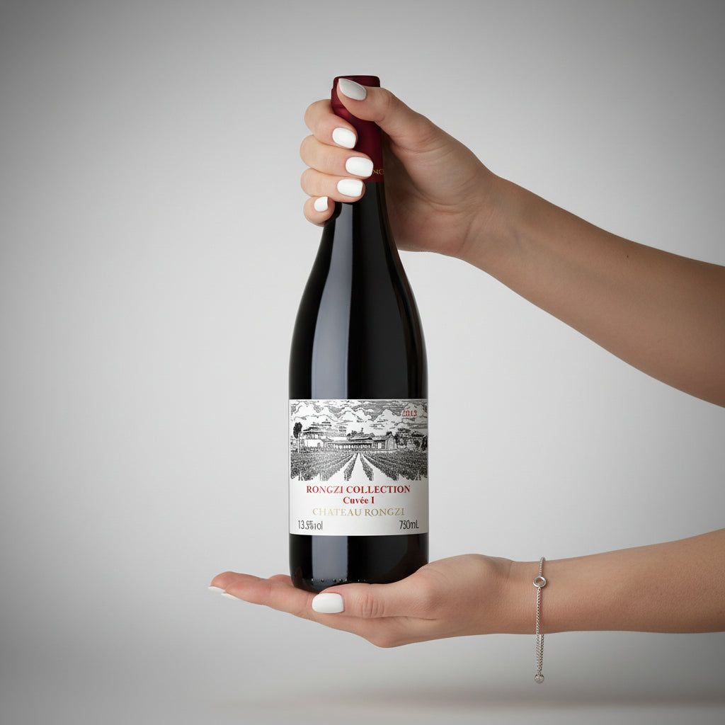 Load image into Gallery viewer, Woman hands holding a bottle of Chateau Rongzi COLLECTION Cuvée I wine with a label against a grey background