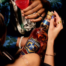 Load image into Gallery viewer, Person holding a bottle of Chivas Regal 18 with a cocktail in the background