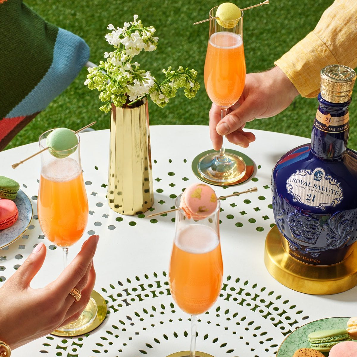 Load image into Gallery viewer, People holding cocktails in flutes with a bottle of Chivas Regal Royal Salute 21 Year Old Signature Blend Scotch Whisky outdoors.