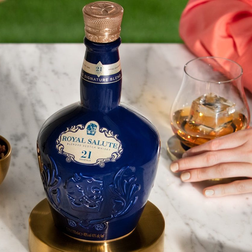 Load image into Gallery viewer, Bottle of Chivas Regal Royal Salute 21 Year Old Signature Blend Scotch Whisky on a marble surface with a glass of whiskey and snacks.