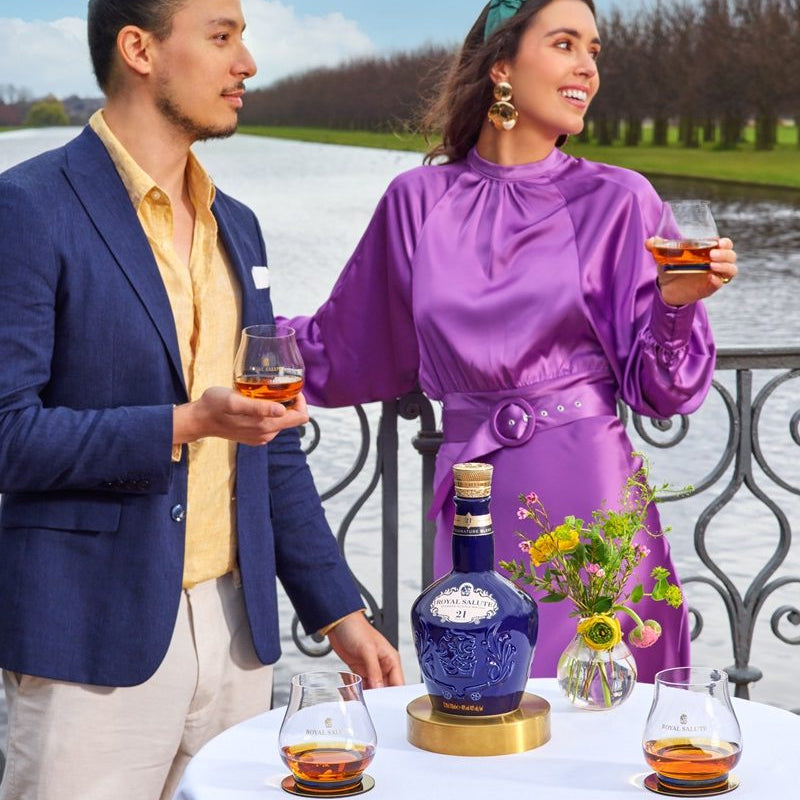 Load image into Gallery viewer, Two people enjoying a drink outdoors with a bottle of Chivas Regal Royal Salute 21 Year Old Signature Blend Scotch Whisky in the foreground.