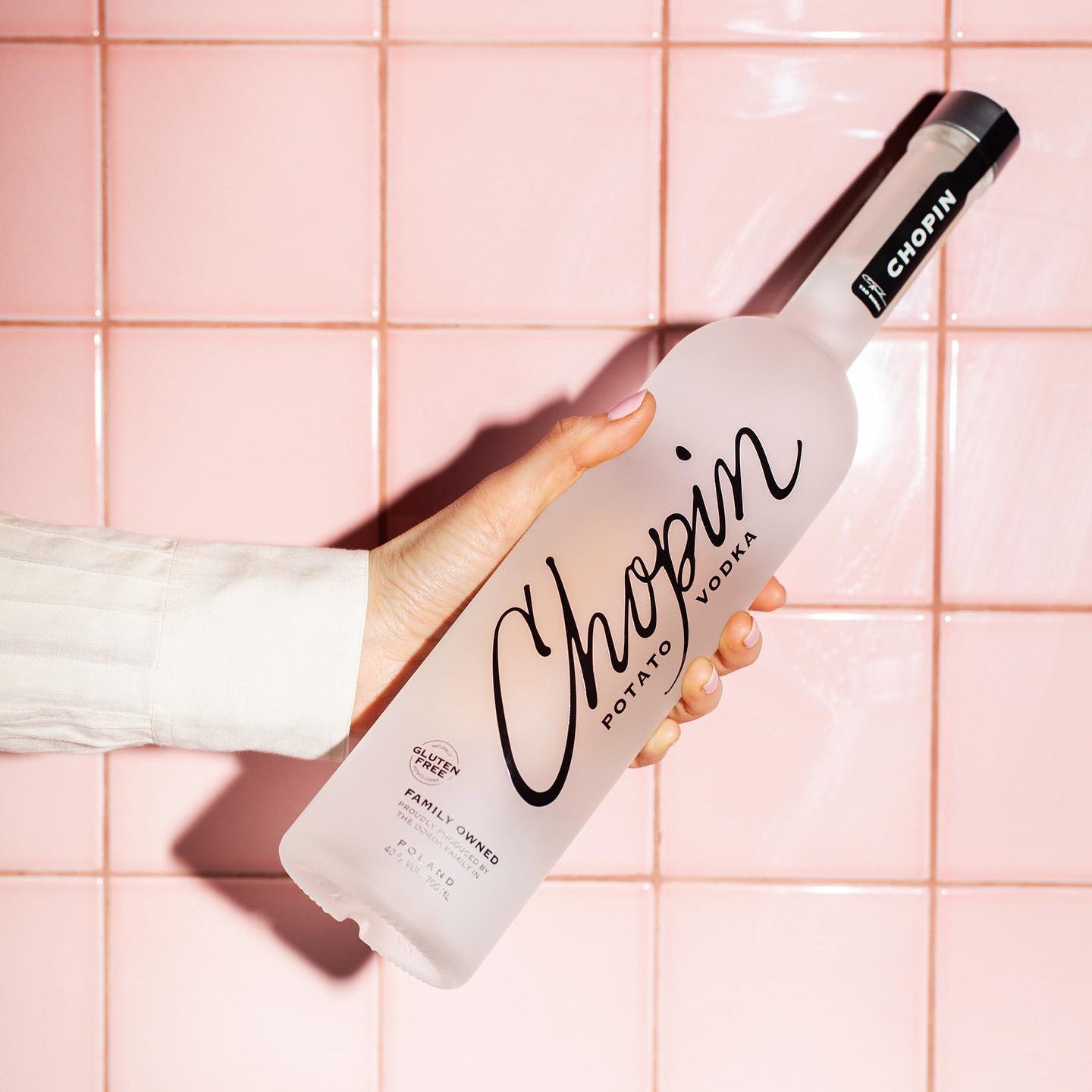 Load image into Gallery viewer, Bottle of Chopin Potato Vodka held against a pink tiled background