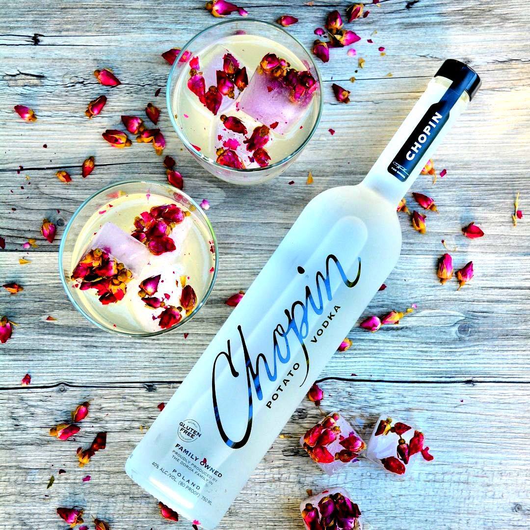 Load image into Gallery viewer, Chopin Potato Vodka bottle with two cocktails garnished with rose petals on a wooden surface.