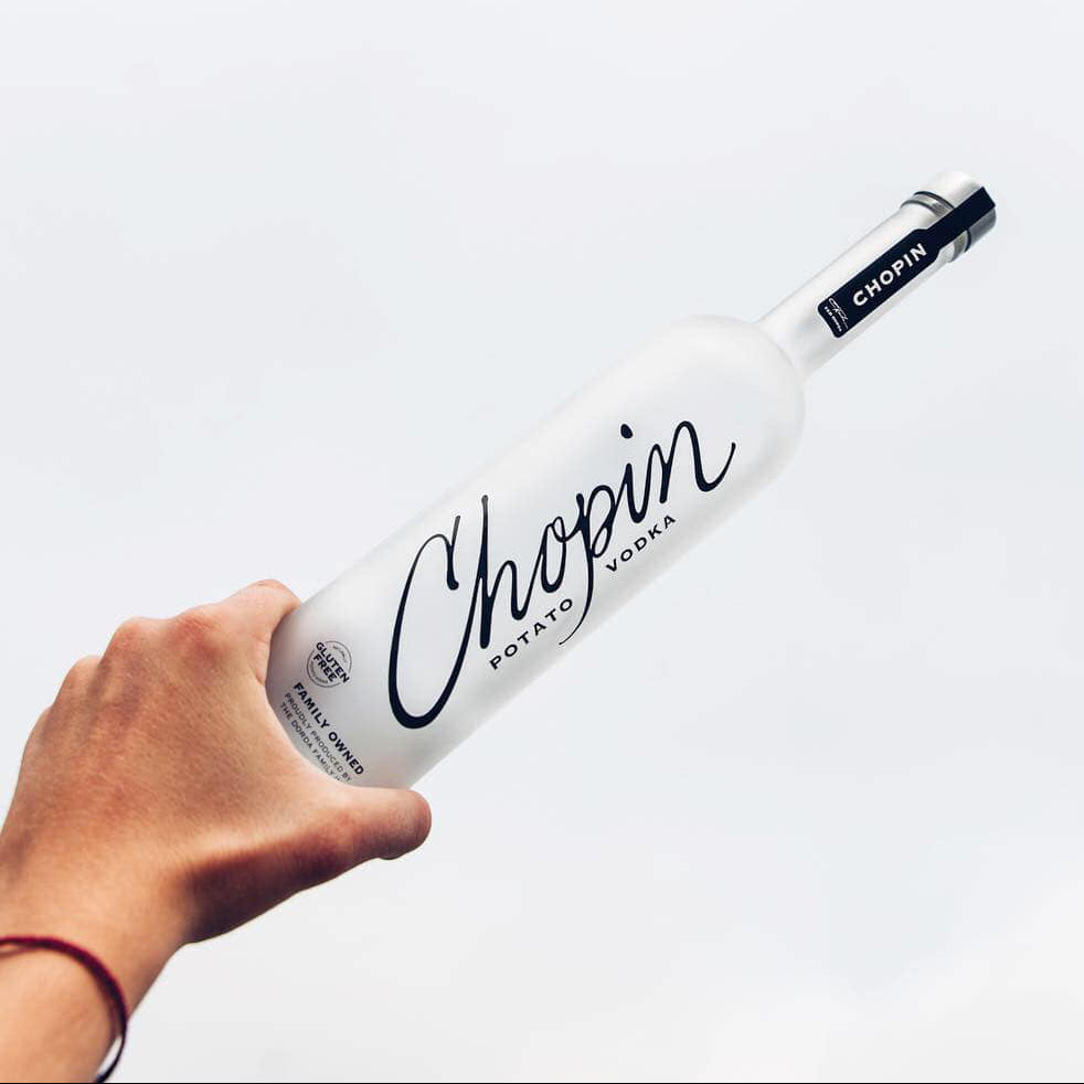 Load image into Gallery viewer, Hand holding a bottle of Chopin Potato Vodka against a white background