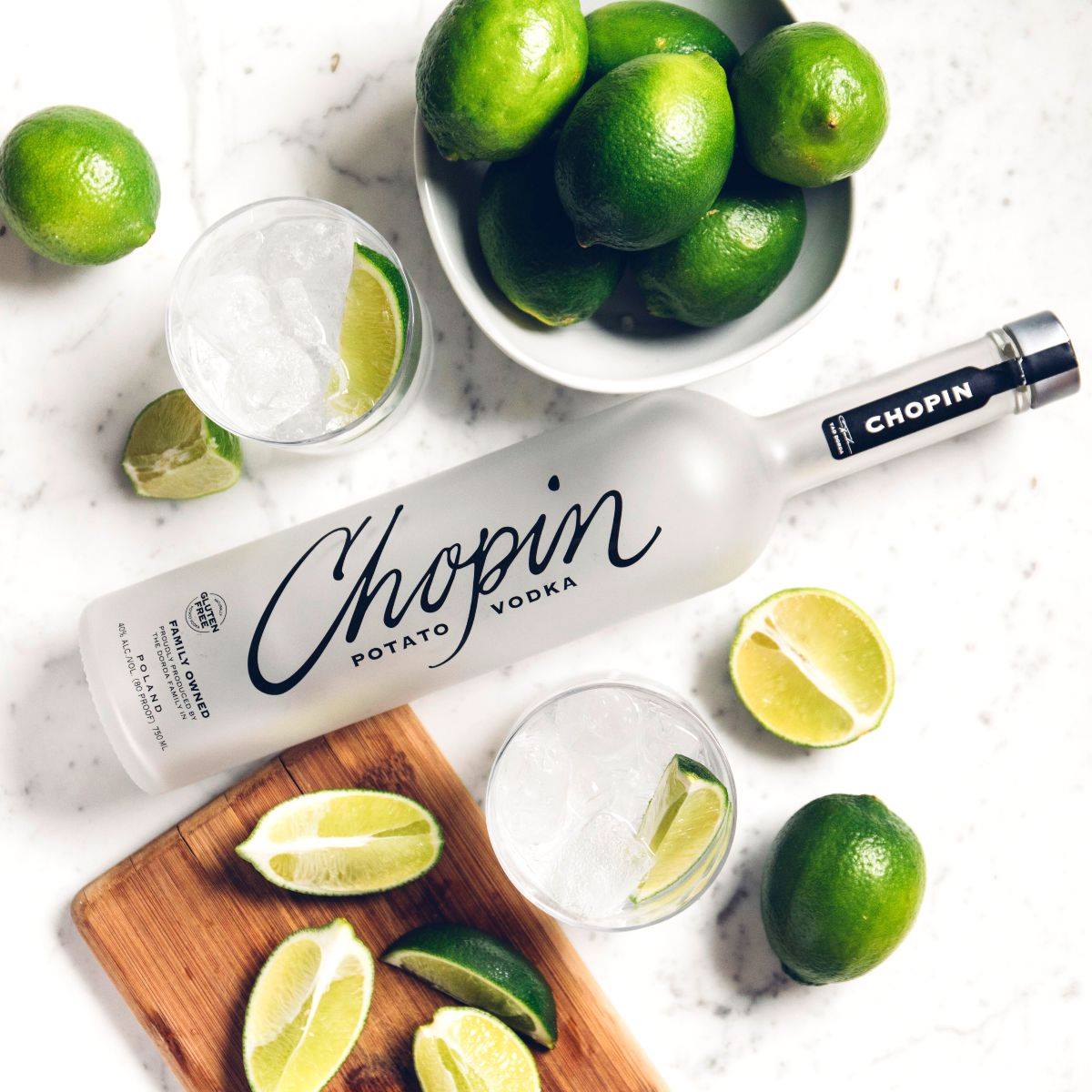 Load image into Gallery viewer, Chopin Potato Vodka bottle with lime wedges and glasses on a marble surface