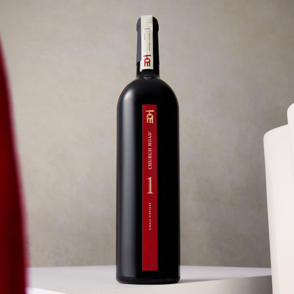 Black wine bottle with red label on a neutral background