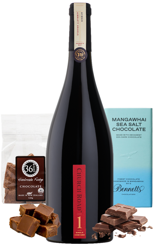 A bottle of Church Road 1 Syrah Red wine centred between packaged chocolate products: a bag of 36 Degrees Handmade chocolate Fudge on the left, a light blue bar of Mangawhai Sea Salt Chocolate by Bennett's on the right, with loose dark chocolate pieces arranged at the base.