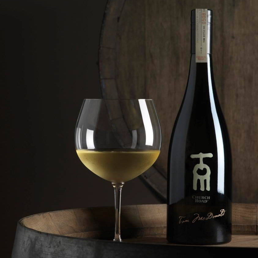 Load image into Gallery viewer, Church Road TOM Chardonnay wine bottle and glass on a wooden barrel with a dark background