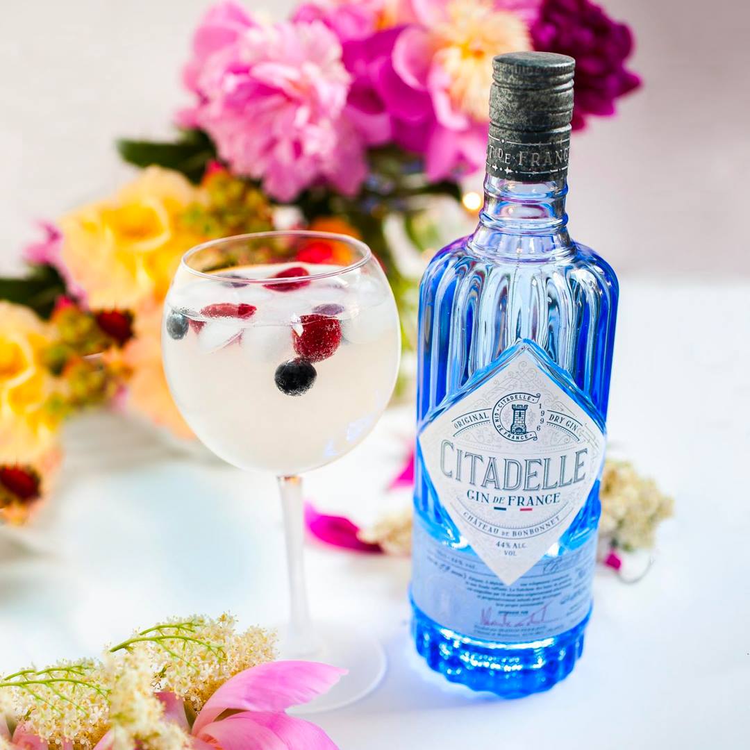Load image into Gallery viewer, Bottle of Citadelle gin with a glass of cocktail and flowers in the background