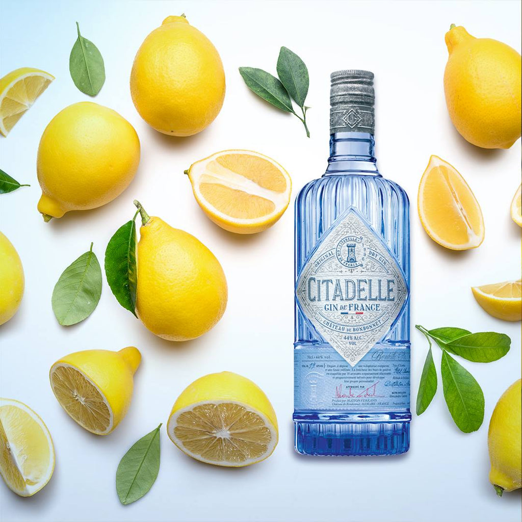 Citadelle gin bottle surrounded by lemons on a white background