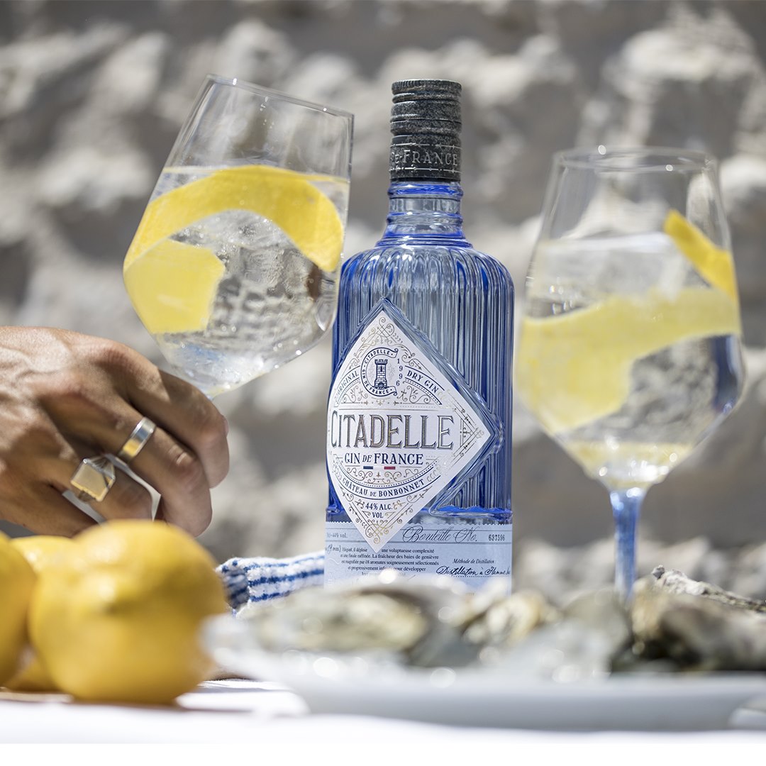 Load image into Gallery viewer, Citadelle gin bottle with two glasses of lemonade on a stone surface