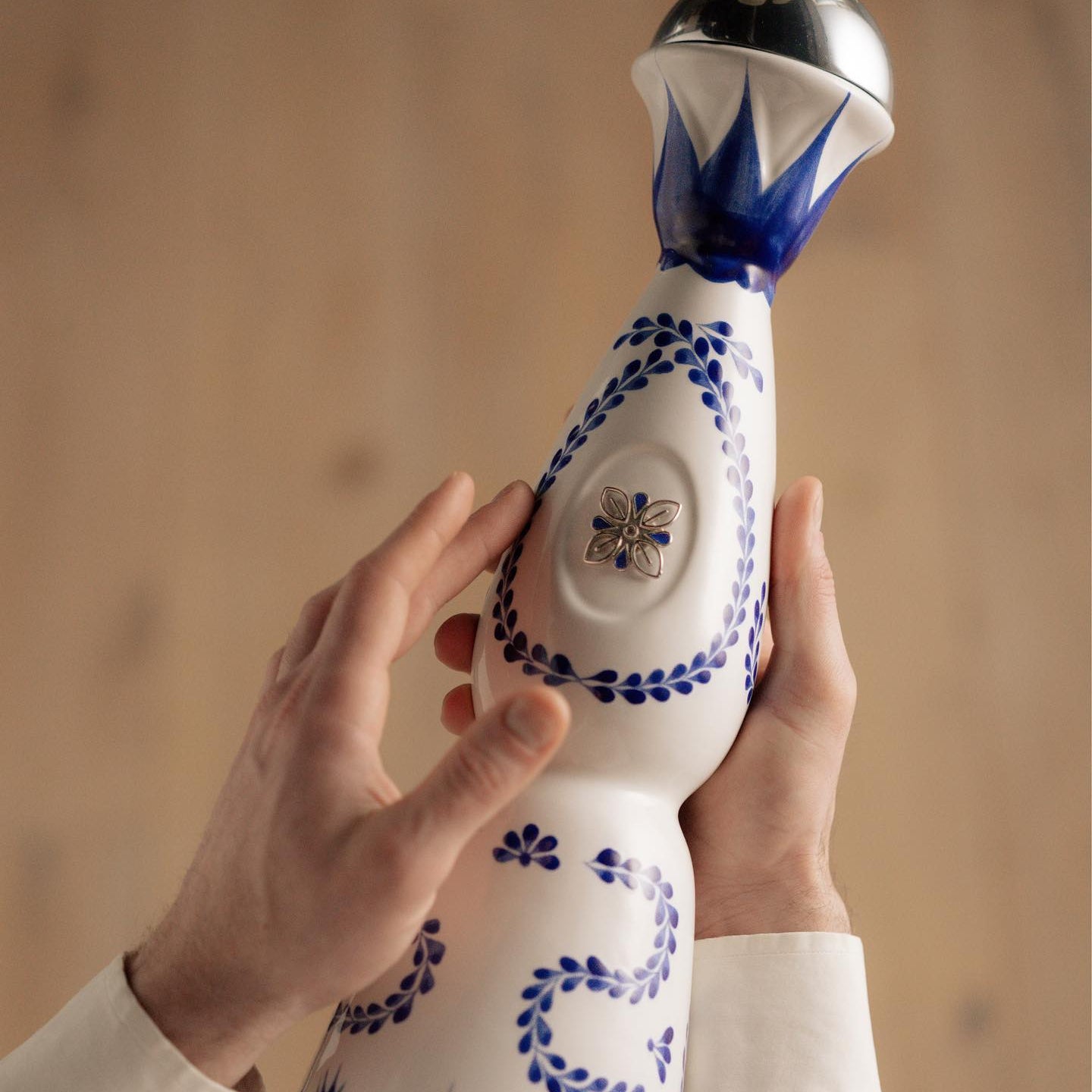 Load image into Gallery viewer, Person holding a bottle of Clase Azul Reposado Tequila against a wooden background