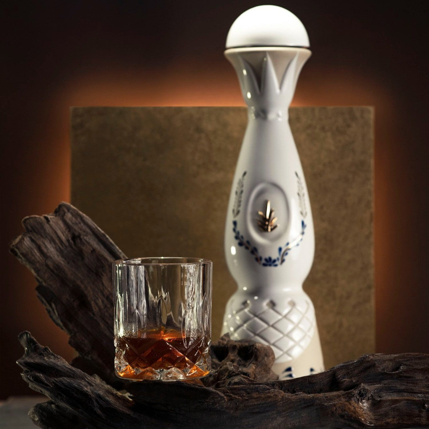Load image into Gallery viewer, A bottle of Clase Azul Reposado Tequila with decorative elements next to a glass of amber liquid on a dark surface.