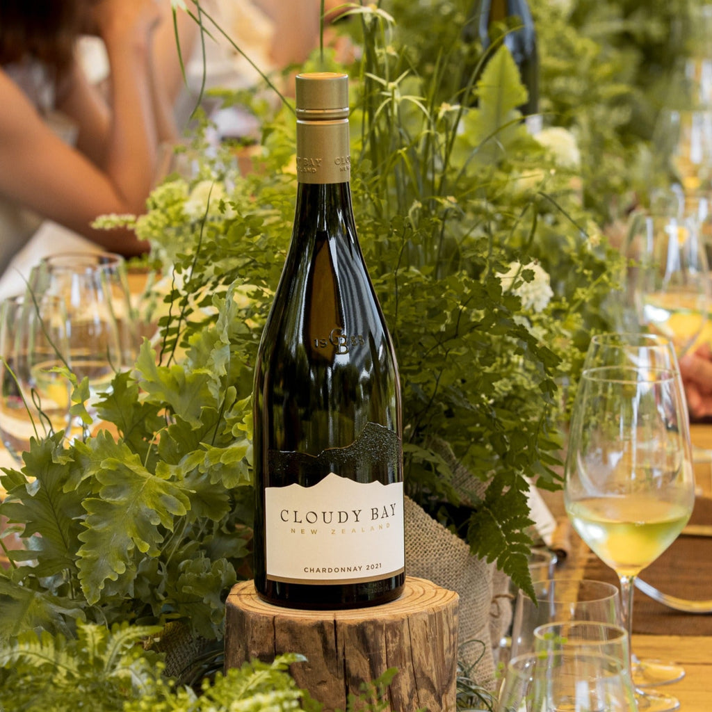 Bottle of Cloudy Bay wine on a table with greenery and glasses.