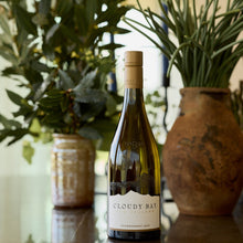 Load image into Gallery viewer, Bottle of Cloudy Bay Chardonnay on a reflective surface with plants in the background