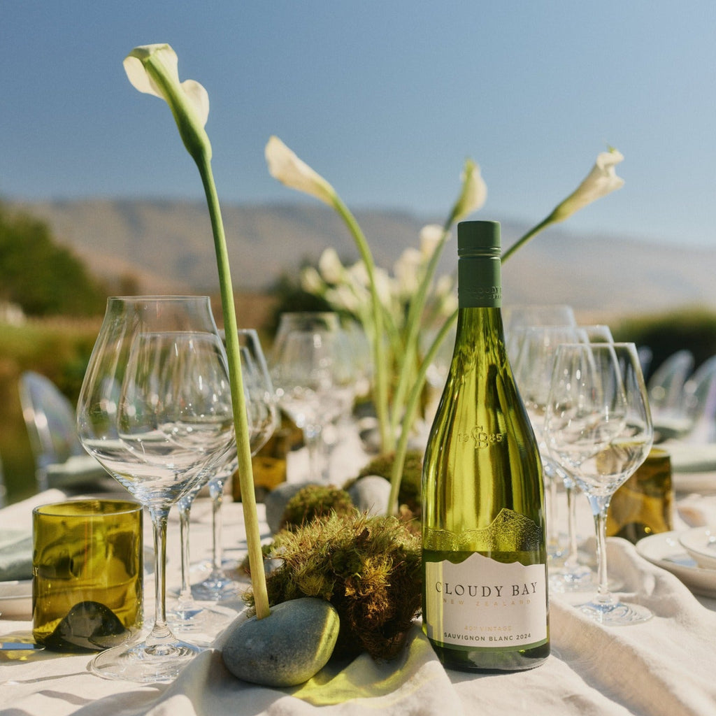Wine bottle on a table with glasses and flowers outdoors