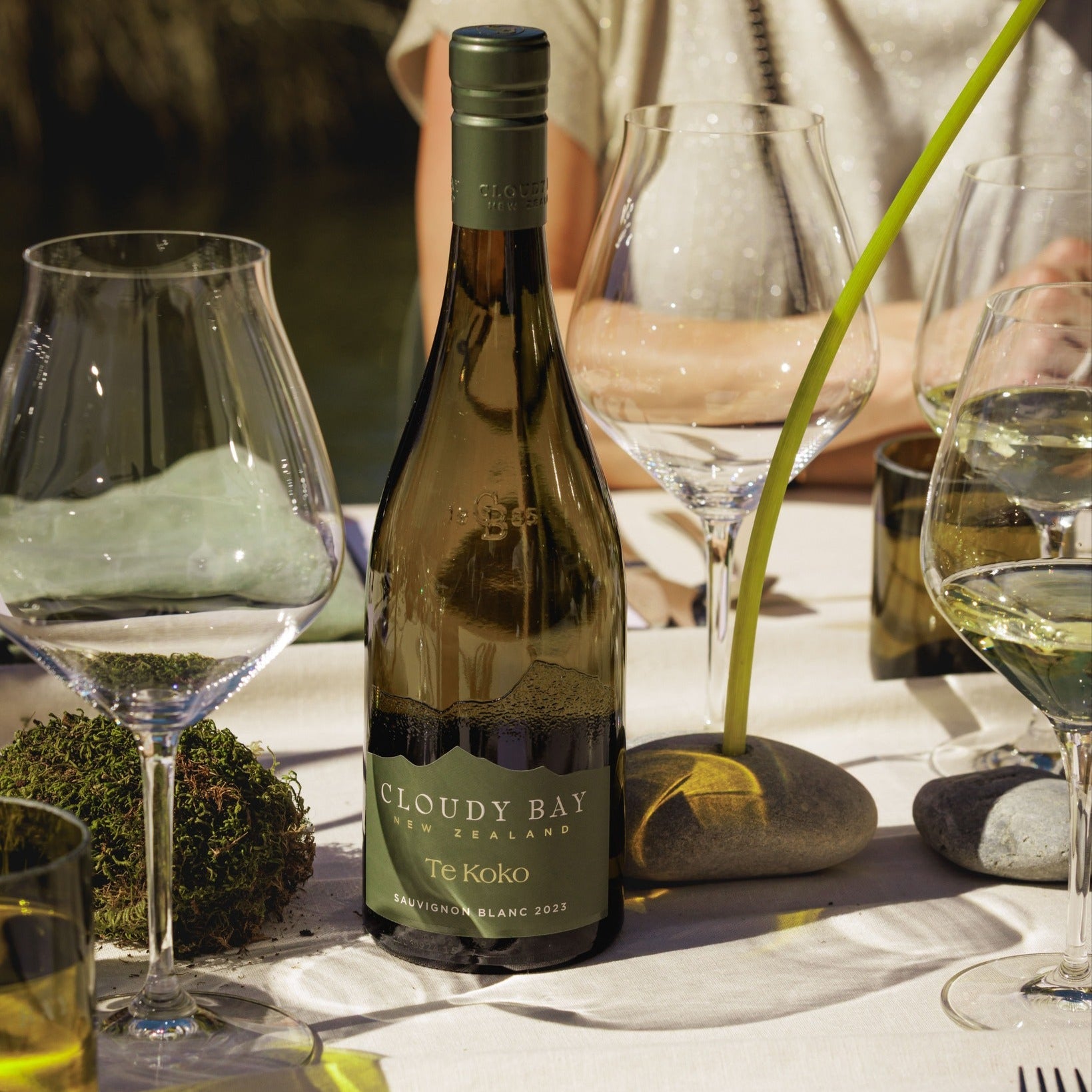Load image into Gallery viewer, Cloudy Bay wine bottle on a table with glasses and decorative elements