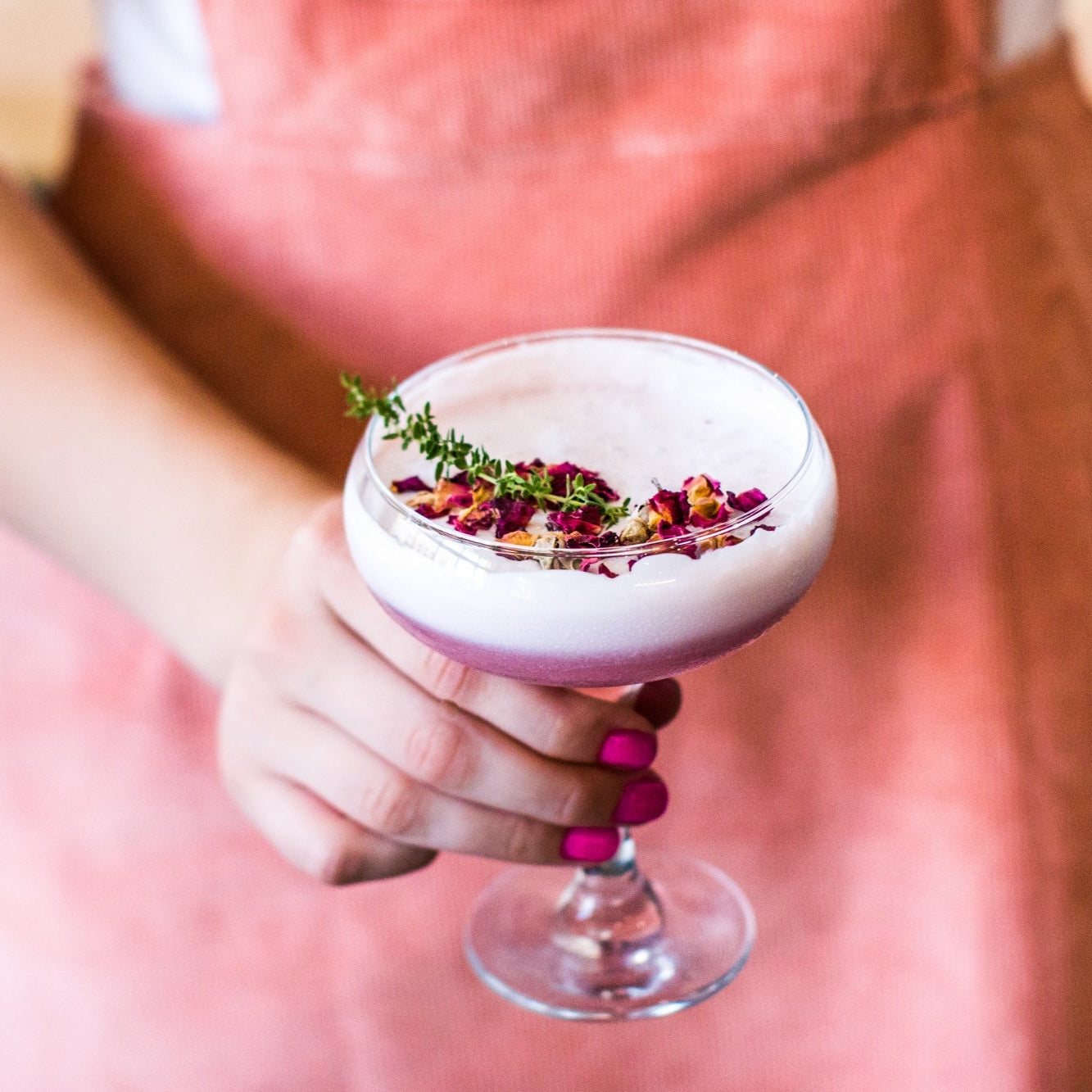 Load image into Gallery viewer, Person holding a pink cocktail with edible dried flower florets garnishes in a bar setting