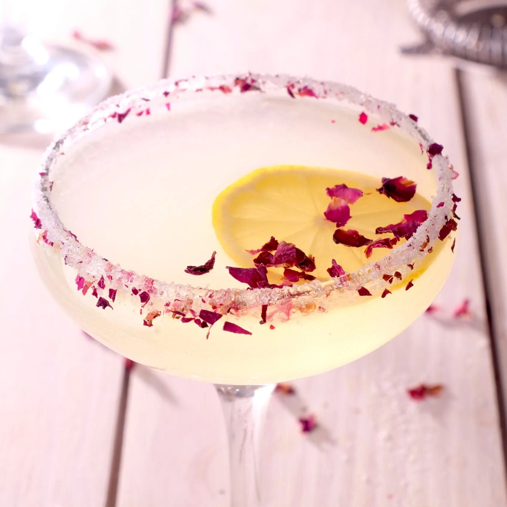 Load image into Gallery viewer, Cocktail with a lemon wheel and rose petals on a wooden surface