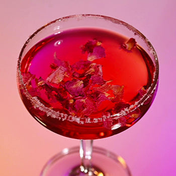 Cocktail with edible dried flowers in a glass against a gradient background