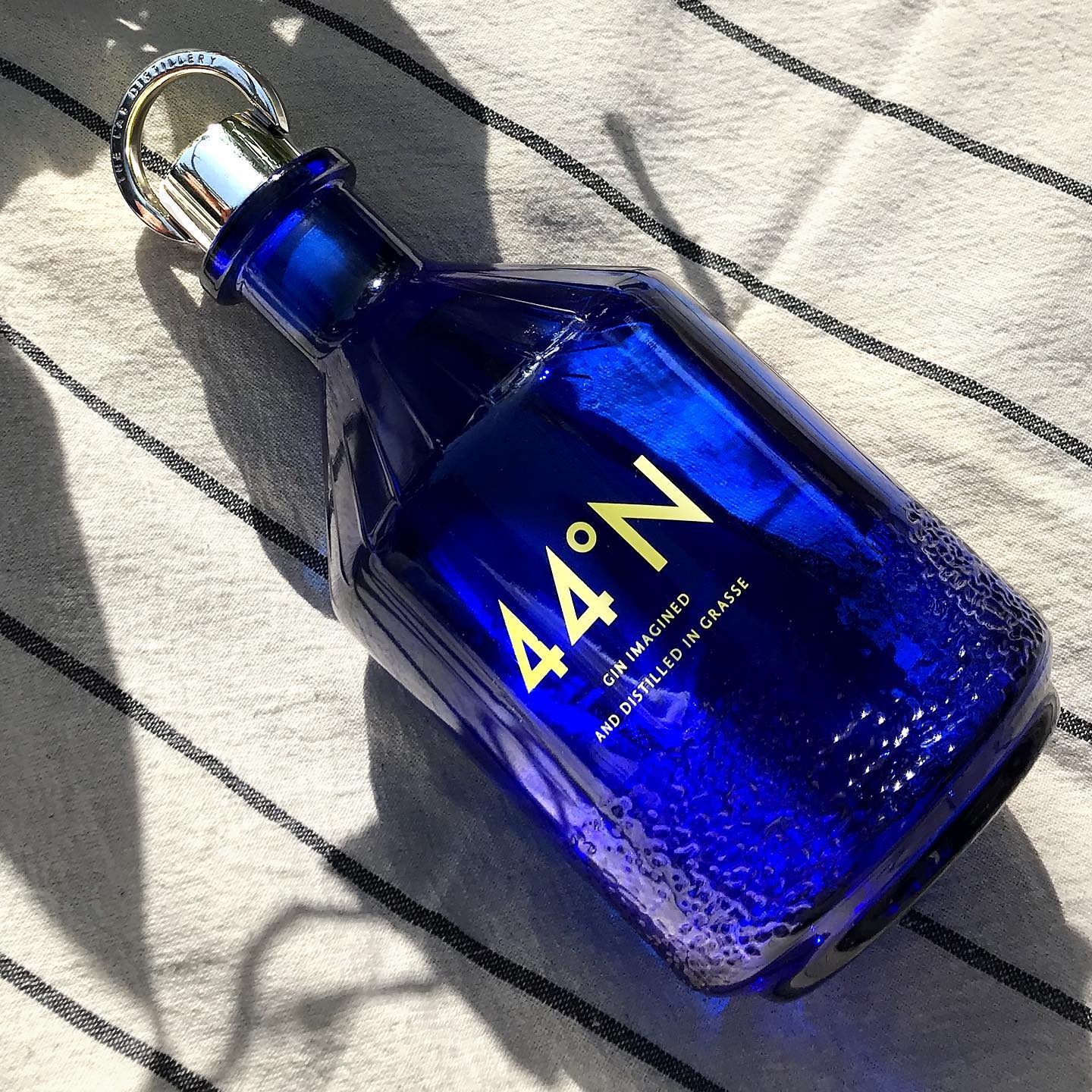 Load image into Gallery viewer, Blue bottle of Comte de Grasse 44 degrees N Gin on a textured surface