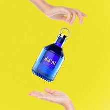 Load image into Gallery viewer, Blue bottle with &#39;44 degrees N gin&#39; label held by a hand against a yellow background