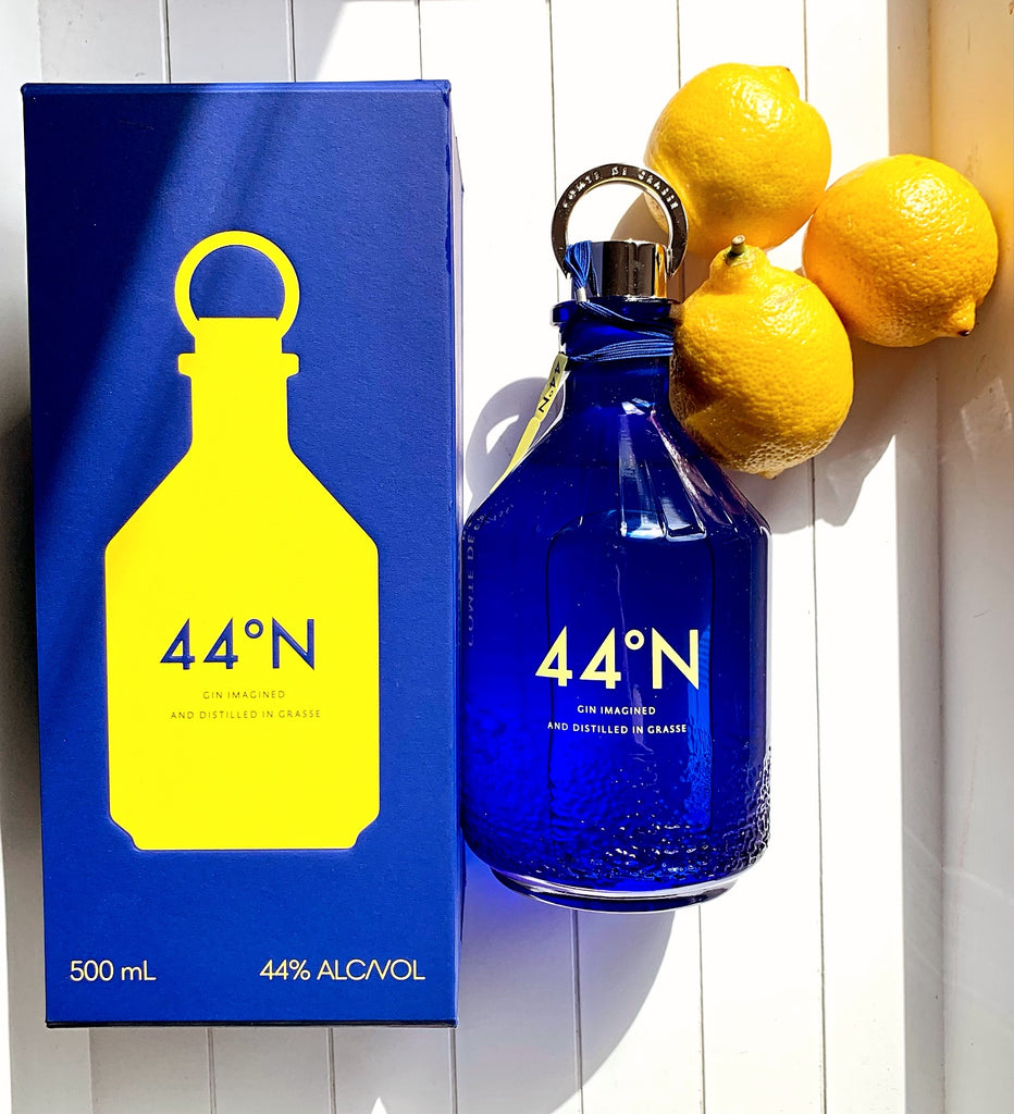 Blue bottle and packaging of 44°N gin with lemons on a white background