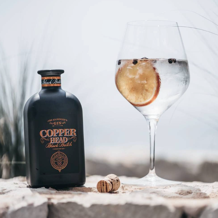 Load image into Gallery viewer, Copperhead Black Batch Gin bottle with a cocktail in a glass on a stone surface