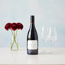 Load image into Gallery viewer, Craggy Range Syrah red wine bottle with two glasses and a vase of red roses on a light surface.