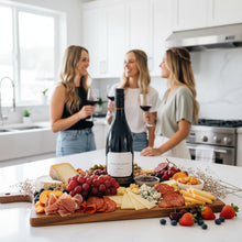Load image into Gallery viewer, Three women in a kitchen enjoying a Craggy Range Syrah red wine and a charcuterie board.