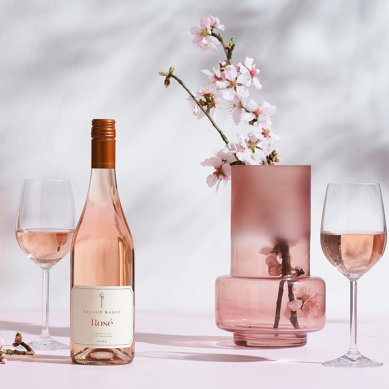 Load image into Gallery viewer, A bottle of Craggy Range Hawke's Bay Rosé and wineglasses and a vase of blossoms