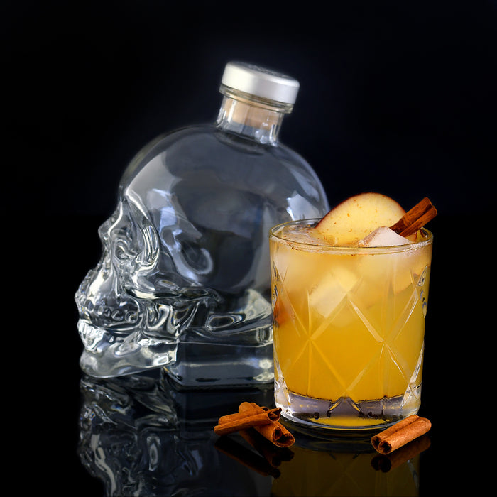 Load image into Gallery viewer, Crystal Head Vodka bottle with a cocktail in a glass on a black background