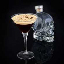 Load image into Gallery viewer, Cocktail in a martini glass with a Crystal Head Vodka bottle on a black background
