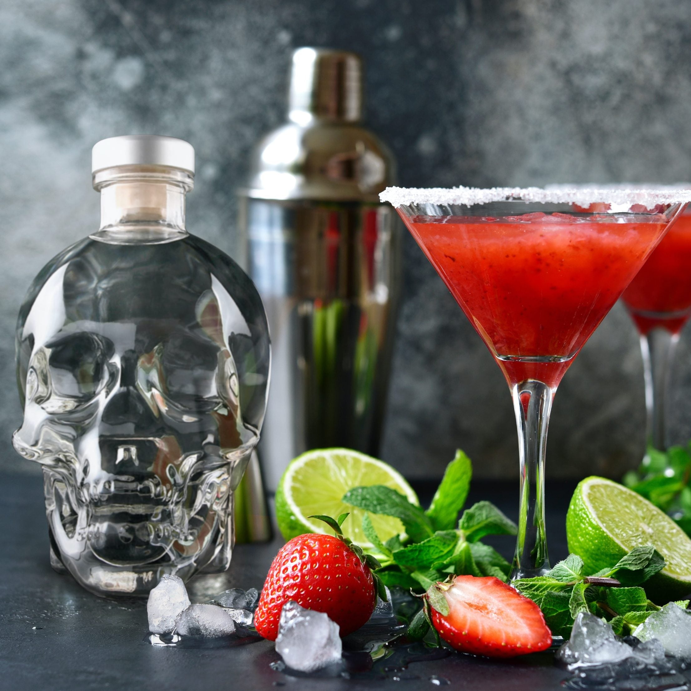 Load image into Gallery viewer, Two red cocktails in martini glasses with a Crystal Head Vodka bottle and cocktail shaker on a dark surface.