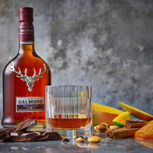 Load image into Gallery viewer, Dalmore whisky bottle with a glass of whisky, fruit, and chocolate on a reflective surface.