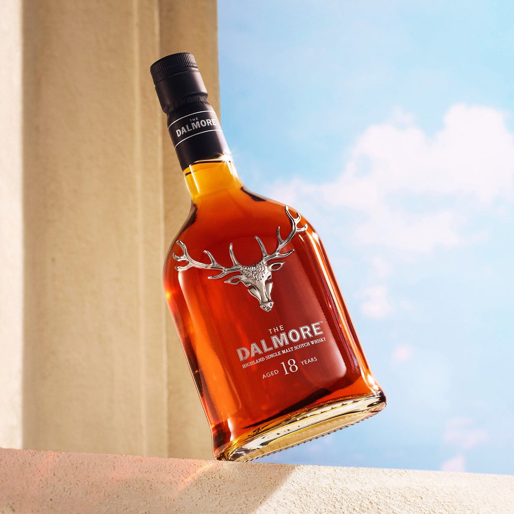 Bottle of Dalmore 18 year old 
whisky against a blue sky and beige wall