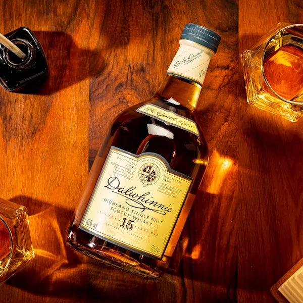 Bottle of Dalwhinnie 15 year old whisky on a wooden surface with glasses.