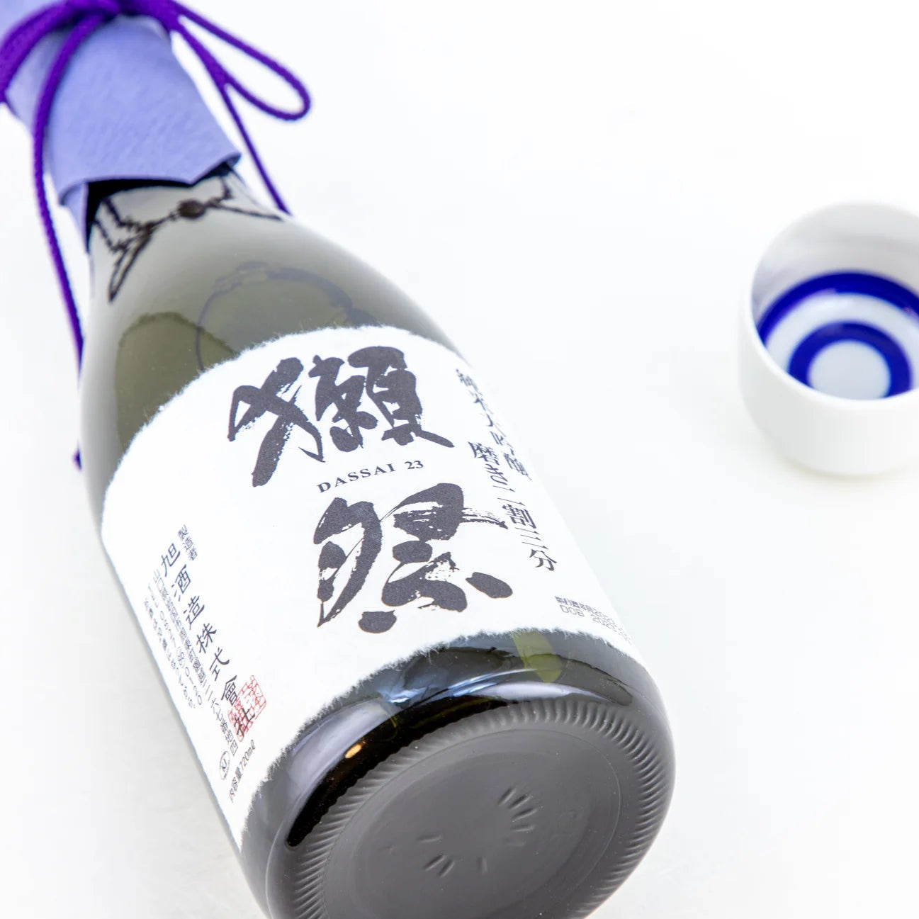 Load image into Gallery viewer, Sake bottle with a purple ribbon and small cup on a white background