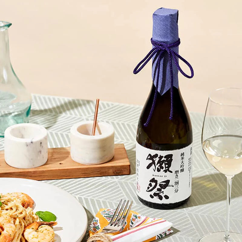 Load image into Gallery viewer, Bottle of Japanese sake with a label on a table set for dining.