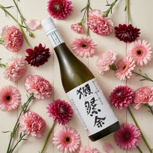 Load image into Gallery viewer, Bottle of Japanese sake surrounded by pink and red flowers on a wooden surface