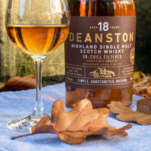 Load image into Gallery viewer, Deanston 18-year-old Scotch whisky bottle with a glass of whisky on a blue cloth with autumn leaves.