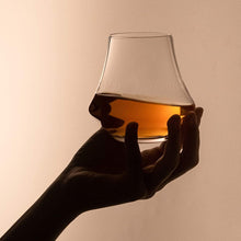 Load image into Gallery viewer, Hand holding a glass of whiskey against a beige background