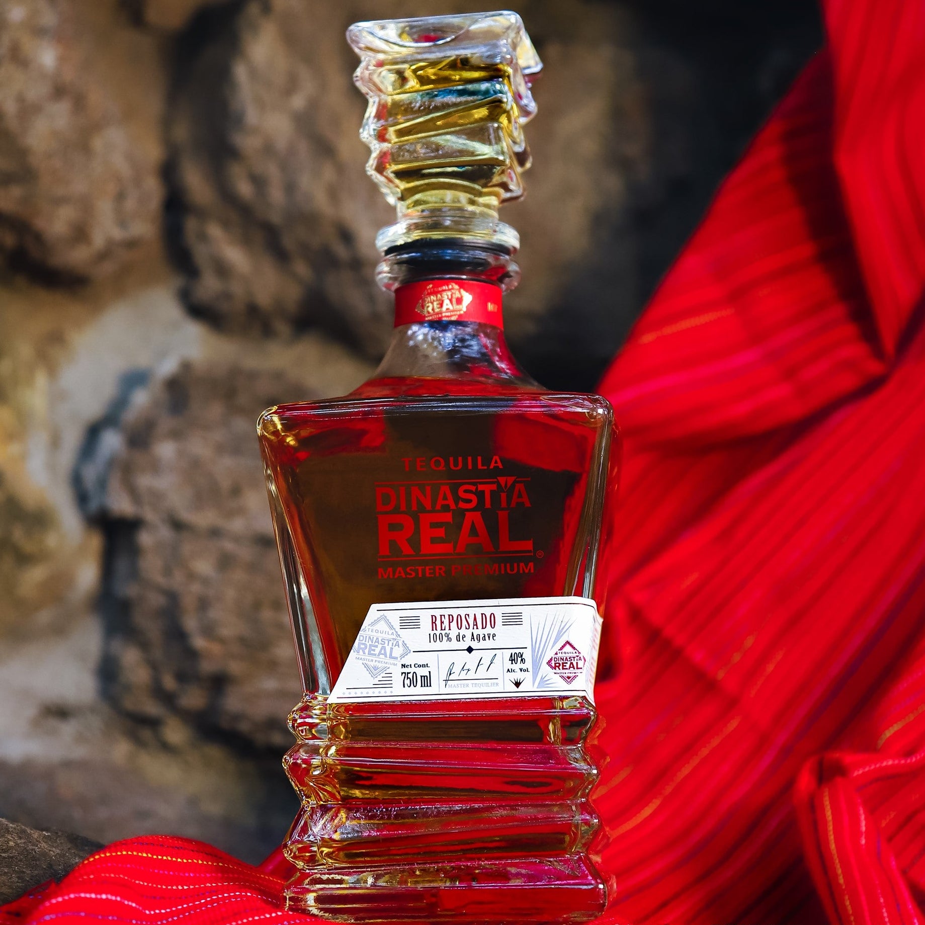 Load image into Gallery viewer, Dinastia Real Master Premium Reposado Tequila bottle with red label on a textured surface