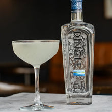 Load image into Gallery viewer, Bottle of Dingle Gin with a cocktail glass on a table against a blurred background