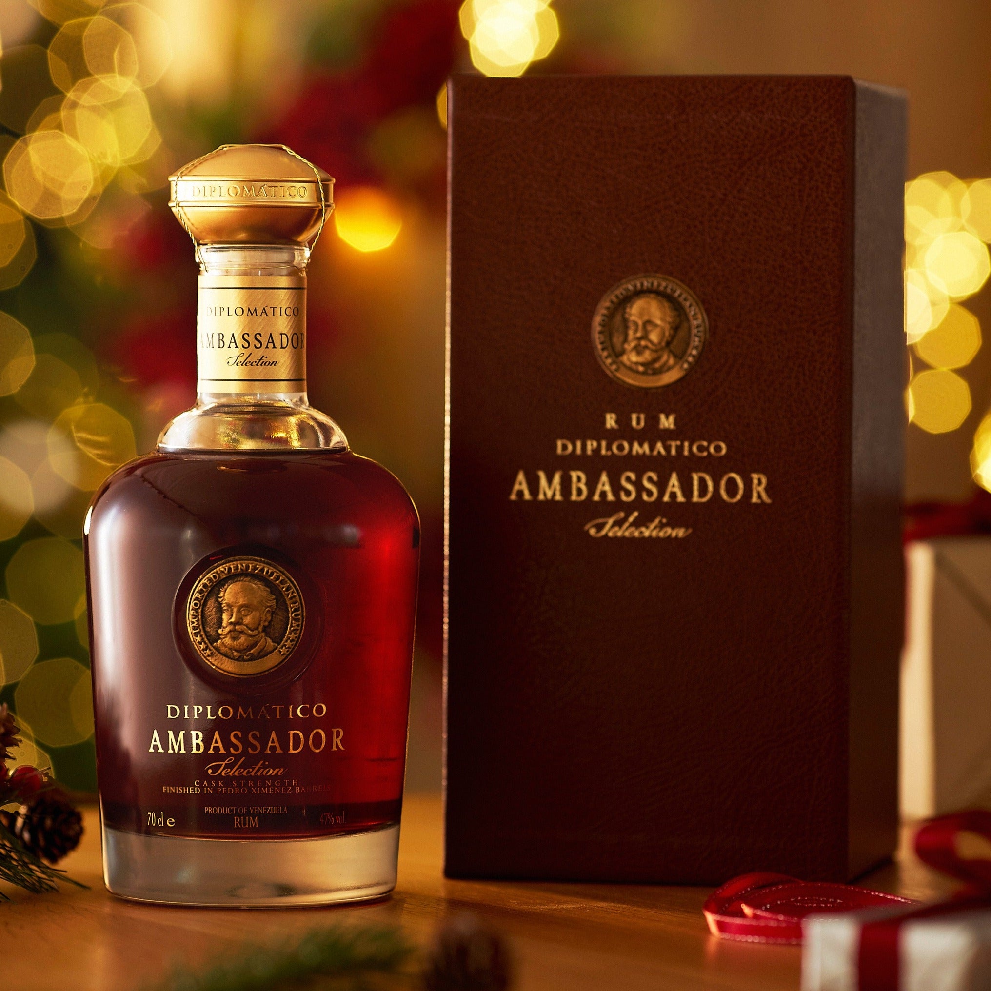 Load image into Gallery viewer, Bottle and box of Diplomatico Ambassador Selection Rum with festive background