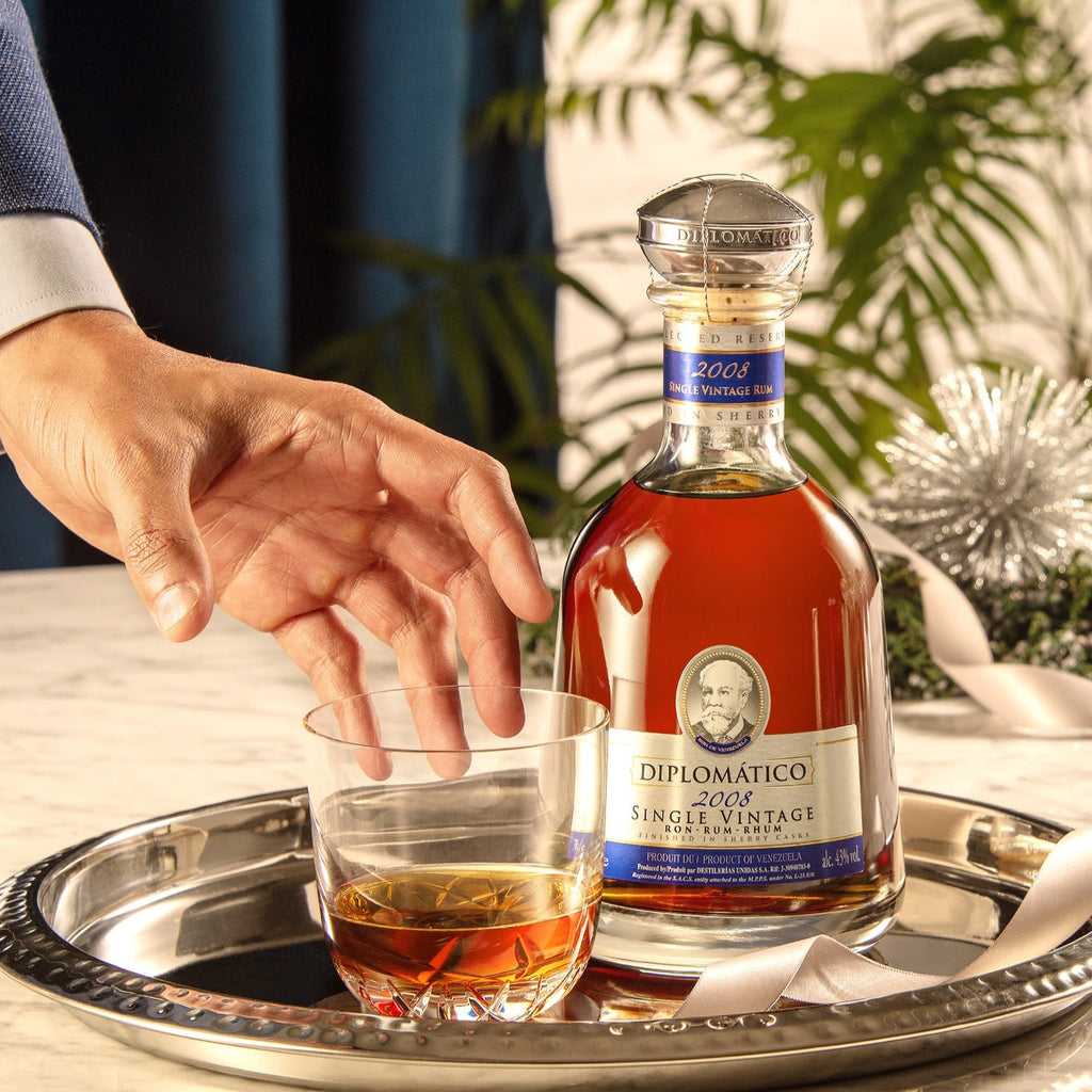 Bottle of Diplomatico rum and a glass on a tray with a blurred background