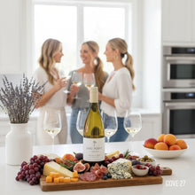 Load image into Gallery viewer, A Dog Point Sauvignon Blanc wine bottle on a charcuterie board with people in the background