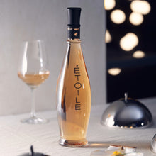 Load image into Gallery viewer, Bottle of Etoile wine with a glass on a table with blurred lights in the background