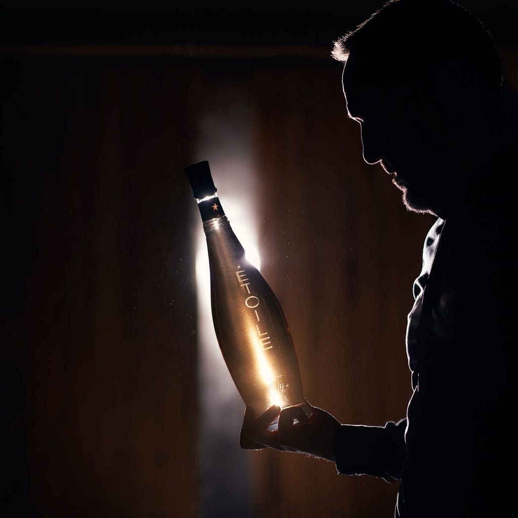 Person holding a bottle of Veuve Clicquot champagne in a dimly lit setting