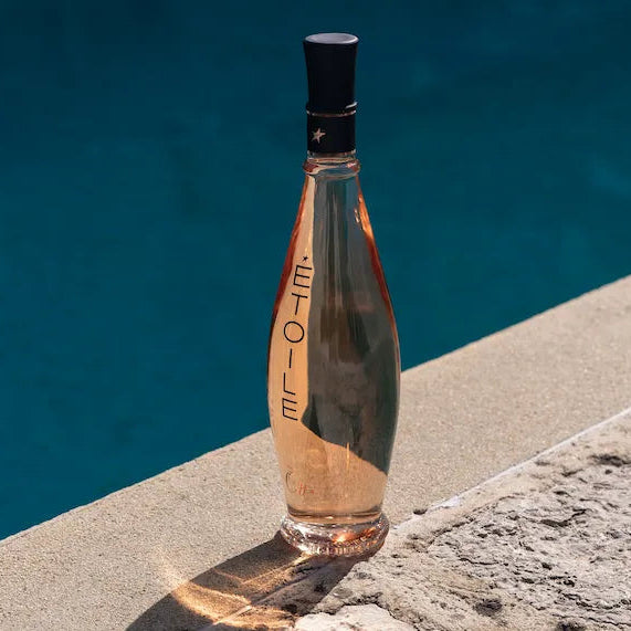 Bottle of Etoile rosé wine against a blue water pool
 background